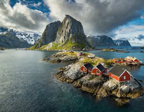 Aerial footage of red houses hanging over the ocean from a small island Hamnoy -Reine- in Lofoten archipelago, northern Norway, with dramatic mountains in the background