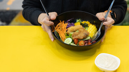 Close-up of woman eating salad in black bowl
