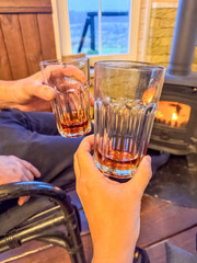 couple hands Toasting by glasses near Fireplace in a Cozy Rustic Cabin Setting. High quality photo
