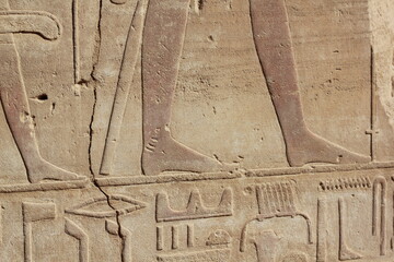 Part of the ancient egyptian scripts and drawings on the wall in Luxor, Egypt. Legs and feet of ancient egyptian people.