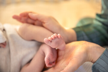 Parent holding in the hands feet of newborn baby. Mom holding baby feet.