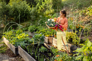 A young woman holding a basket filled with freshly harvested vegetables and vibrant flowers in a...