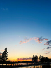 Fototapeta premium Tranquil lakeside sunset with silhouettes and vibrant sky