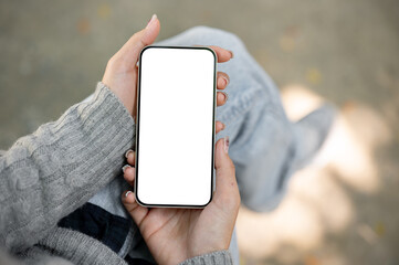 A close-up of a smartphone mockup in a woman's hand, set against a blurred outdoor background.