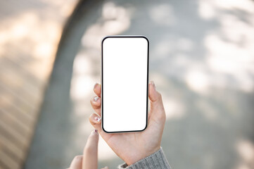A close-up of a woman sitting outdoors in a park, using her smartphone, touching the screen.