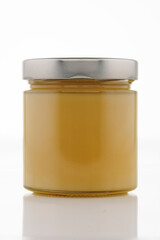 Jar with white honey, glass jar with metal lid, close-up. Isolated on white background