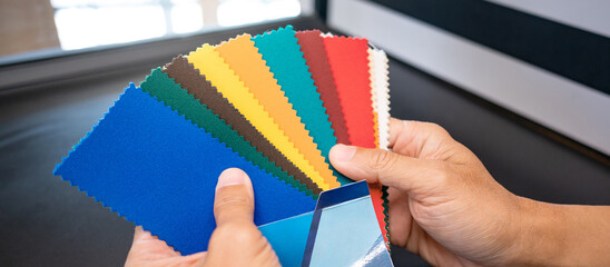 Fabric swatch material choice. Designer hand choosing fabric sample pieces from color collection...