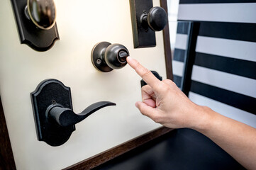 Designer hand pointing at vintage door knob with lock on sample collection in hardware store. Choosing door hardware for retro home interior design element