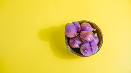 red onion in wooden bowl on yellow background 