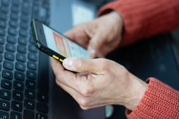 a woman's hands manipulating a cell phone in her office