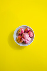 red onion in white bowl on yellow background 