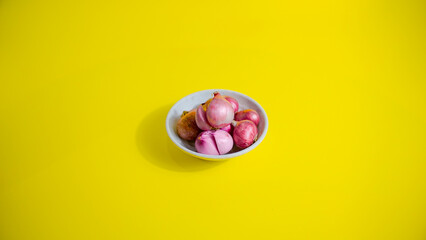 red onion in white bowl on yellow background 