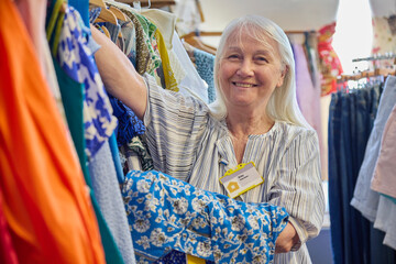 Portrait Of Senior Female Volunteer Working In Charity Shop Or Thrift Store Selling Used And Sustainable Clothing