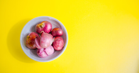 red onion in white bowl on yellow background 