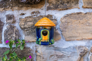 A charming miniature house delicately suspended from an old grapevine branch