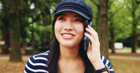 Park, woman and happy with conversation on phone call for communication, contact and gossip in Japan. Outdoor, female person and smile at forest with listening for update, connection and discussion