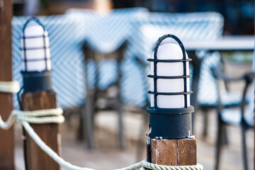Charming Outdoor Café Lighting with Wooden Posts and Nautical Rope © bubbers