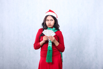 Beautiful young indonesia woman wearing Christmas sweater, Santa hat and scarf, pouting annoyed to...