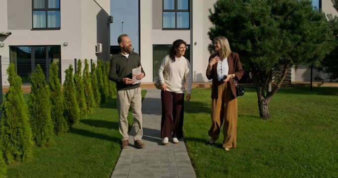 A man and a woman use the services of a realtor. They talk as they walk through the backyard of a stylish townhouse