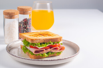 Close-up of two sandwiches with bacon, salami, prosciutto and fresh vegetables on rustic wooden cutting board. Club sandwich concept