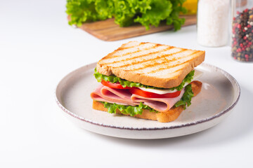 Close-up of two sandwiches with bacon, salami, prosciutto and fresh vegetables on rustic wooden cutting board. Club sandwich concept