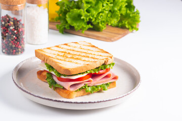 Close-up of two sandwiches with bacon, salami, prosciutto and fresh vegetables on rustic wooden cutting board. Club sandwich concept
