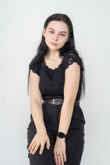 Cute young brunette girl sitting on a white background. Copy space