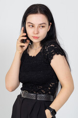 Cute young brunette communicating with smartphone on a white background. Copy space