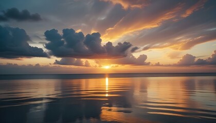 Obraz premium Una espectacular puesta de sol sobre un océano en calma, con vibrantes nubes de color naranja, amarillo y azul reflejándose en el agua tranquila. El sol se pone detrás de las nubes, creando una impres
