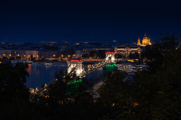 Obraz premium Budapest chain bridge at night in color of Hungarian national flag. Szechenyi Bridge from Budapest, Hungary, night blue hour landmark photo. Travel to Budapest.
