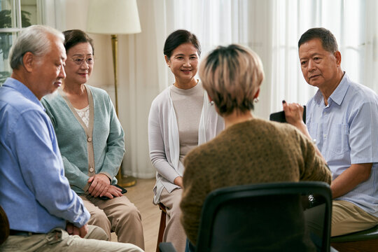asian counselor facilitating a group discussion for senior people