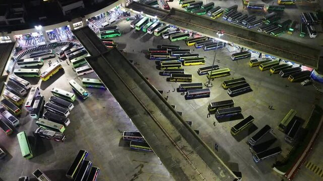 Drone zoom-in shot of dozens of busses at the world's biggest bus terminal, the Kilambakkam Bus Terminus in Chennai, India. Night time