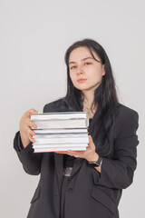 Fototapeta premium Young cute brunette girl with a stack of books on a white background. Copy space