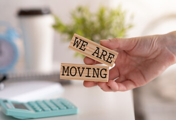 We are moving symbol. Concept word We are moving on wooden blocks. Businessman hand. Beautiful blue background. Business and We are moving concept.