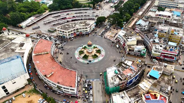 Drone shot orbiting the vibrant roundabout featuring the Statue of Nalwadi Krishna Raja Wodeyar in Mysore, India. Surrounded by bustling streets.