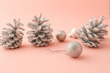 Close-up of silver glitter pinecones and Christmas ornaments arranged on a pastel pink background. Perfect for festive, holiday, and minimalistic seasonal designs or advertisements