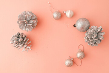 Festive arrangement of silver glitter pinecones and ornaments on a pastel pink background. Minimalist and elegant design for Christmas and holiday-themed projects or decorations