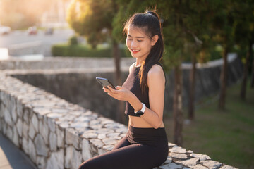 Happy Active healthy asian woman use mobile cell phone exercising with smartphone at urban street outdoors fitness and phone