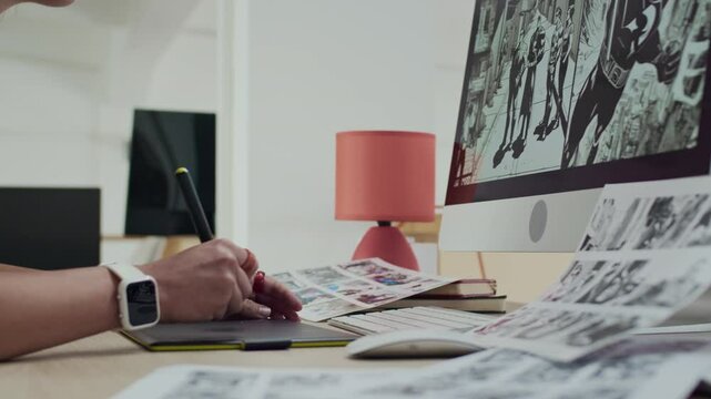 Tilt down shot of focused Caucasian female graphic artist sketching comics on tablet while working in creative environment of bright modern office