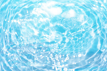 Blue water with ripples on the surface. Defocus blurred transparent blue colored clear calm water surface texture with splashes and bubbles. Water waves with shining pattern texture background.