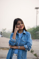 Fototapeta premium Portrait of serious beautiful female, looks smiling at camera, stands against natural background stock photo