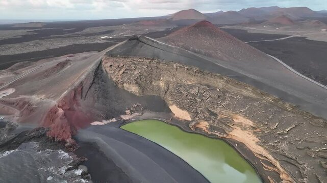 Aerial view of a beautiful green lake surrounded by volcanic landscape and mountains, Yaiza, Spain.