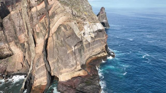 Aerial view of breathtaking cliffs and rugged rock formations by the serene ocean waves, Dorgali, Italy.