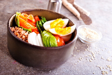 Healthy vegan nutritious bowl with buckwheat. Salad of avocado, salmon, buckwheat, egg and tomato, top view