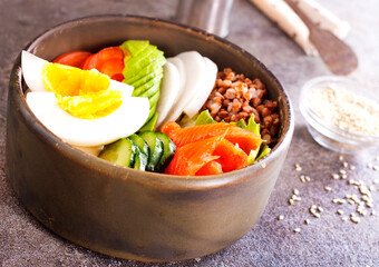 Healthy vegan nutritious bowl with buckwheat. Salad of avocado, salmon, buckwheat, egg and tomato, top view