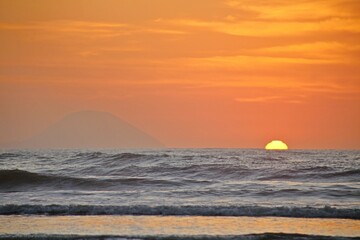 Sun rising on the horizon over the sea waters. Reflections of gold-colored sunlight, ocean waves