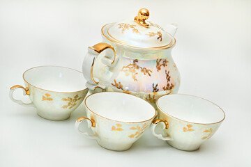 Tea time.Porcelain antique retro teapot, three cups with golden line drawings