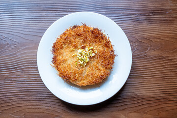 Close-up of local Turkish dessert kunefe with pistachios on a white plate