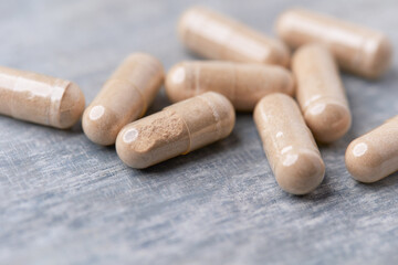 Reishi capsules. Concept for a healthy dietary supplementation. Wooden background. Soft focus. Close up.	