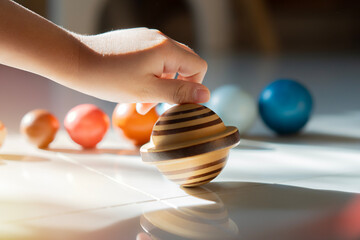 Young boy playing with a colorful toy solar system model. Educational toys concept.